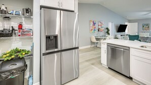Une cuisine moderne équipée d’appareils électroménagers en acier inoxydable, d’un lave-vaisselle et d’un coin repas avec une table et des chaises.