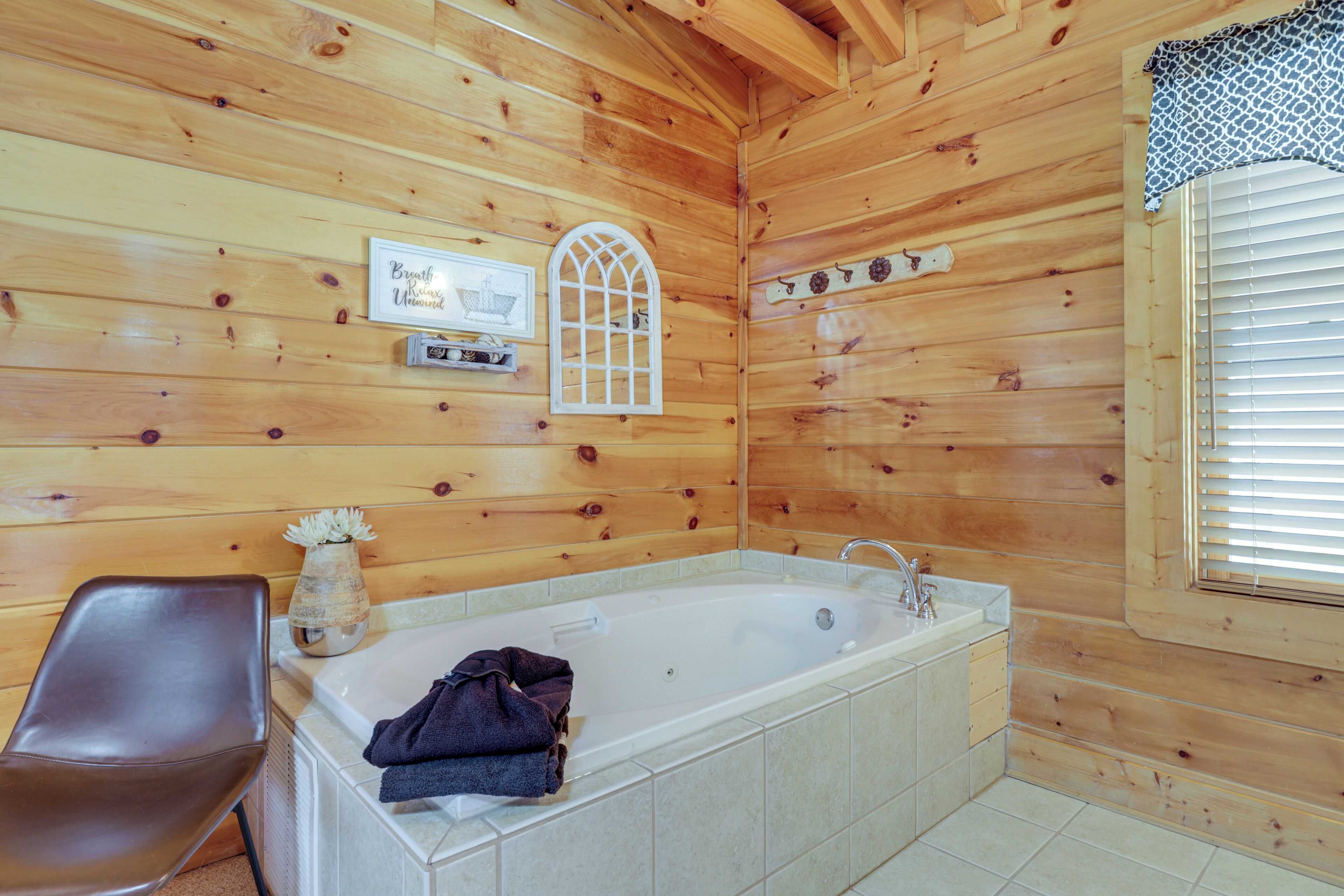 Bagno di una cabina di legno con una vasca, una sedia e una finestra con persiane.