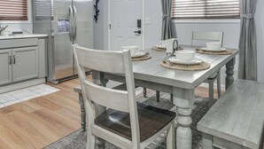 A dining area with a wooden table, chairs, and a refrigerator. - Brand-New Sequim Escape: A/C, Fire Pit, Grill (Sequim)