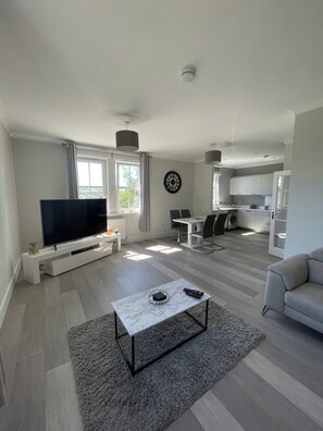 A modern living room with a flat-screen TV, a marble coffee table, and a grey sofa. - Spacious Apartment in Aberdeenshire (Insch)