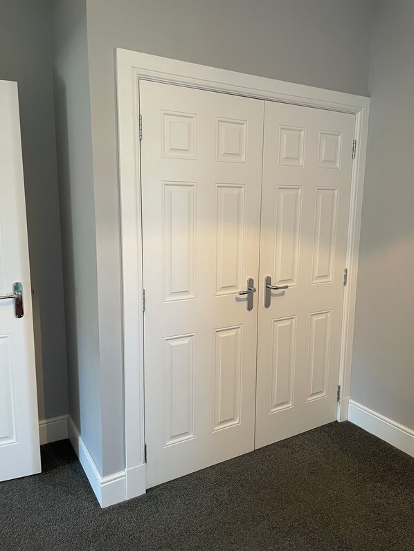 A closed white door with a handle, a white door with a handle, and a dark carpeted floor. - Spacious Apartment in Aberdeenshire (Insch)