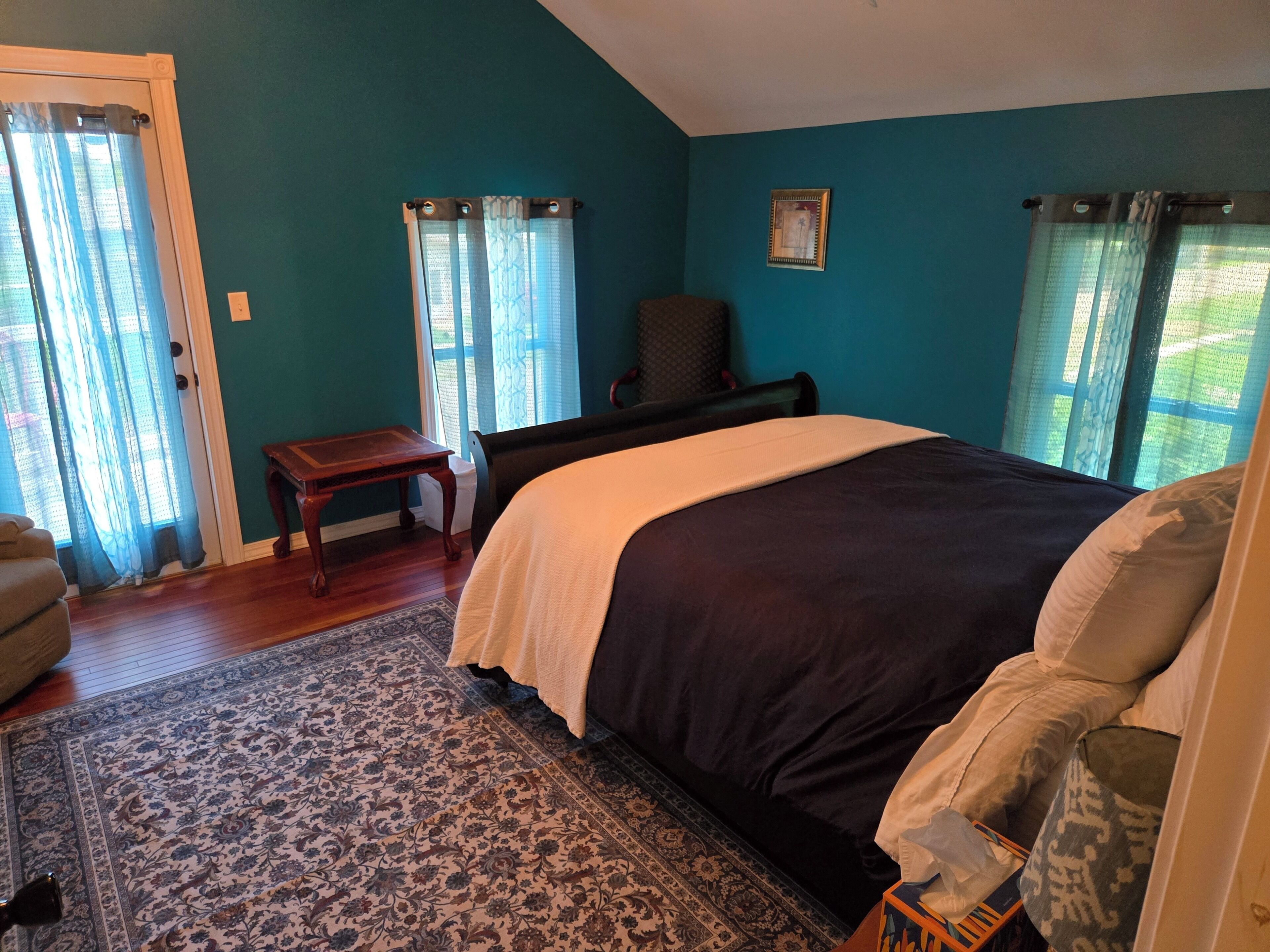 Ein Schlafzimmer mit einem Bett, einem Sessel, einem kleinen Tisch und einem Teppich.
