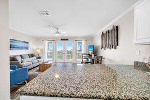 A spacious living area with a large granite island, a sofa, a coffee table, and a television. - Gulf Place Caribbean 406 (Santa Rosa Beach)