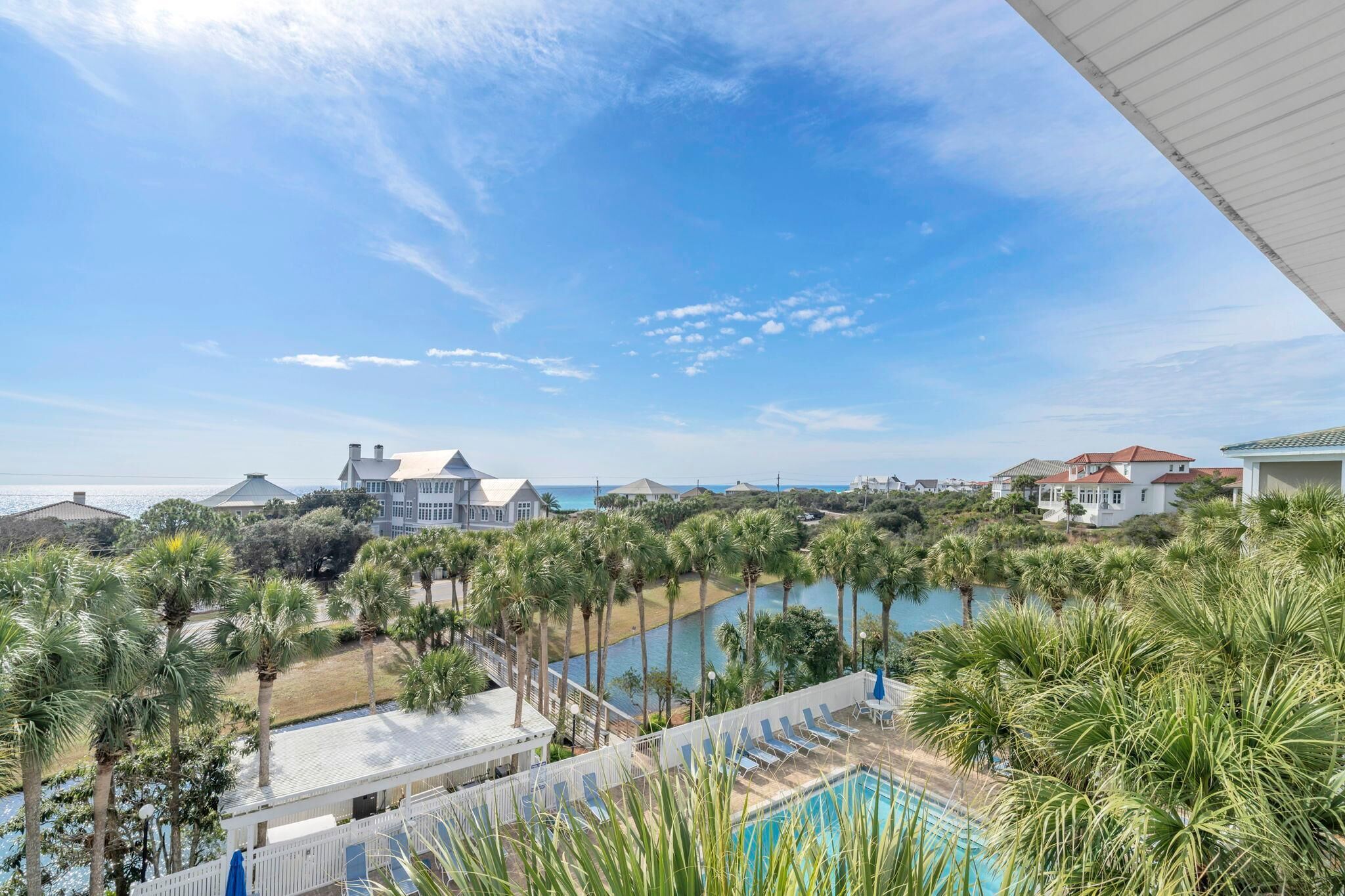 A resort with a pool, palm trees, and a view of the ocean.