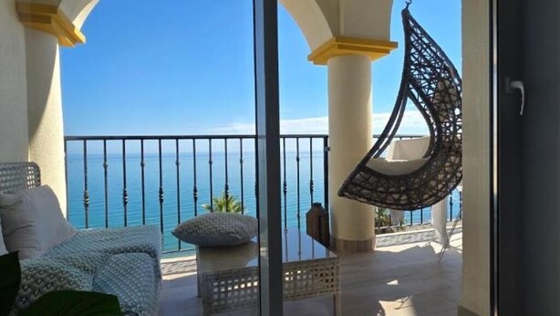 A balcony with a hanging chair, a sofa, and a view of the sea. - Comfort with the best ocean view at the Marina Balcony (benalmadena)