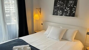 A hotel room with a neatly made bed, a wall-mounted light, and a tropical-themed painting. - Comfort with the best ocean view at the Marina Balcony (benalmadena)