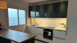 A modern kitchen with a large window, white brick backsplash, and dark cabinets. - Comfort with the best ocean view at the Marina Balcony (benalmadena)
