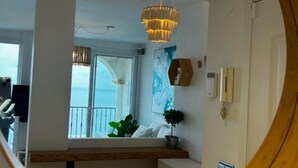A room with a large window, a chandelier, a plant, and a wooden bench. - Comfort with the best ocean view at the Marina Balcony (benalmadena)