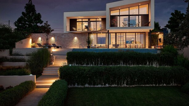 A modern two-story house with a swimming pool, outdoor seating, and a well-lit entrance. - Luxury 4BR Seafront Villa with Pool and Jacuzzi (Sućuraj)