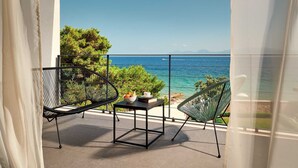 A balcony with a table and two chairs, overlooking a clear blue sea and greenery. - Luxury 4BR Seafront Villa with Pool and Jacuzzi (Sućuraj)