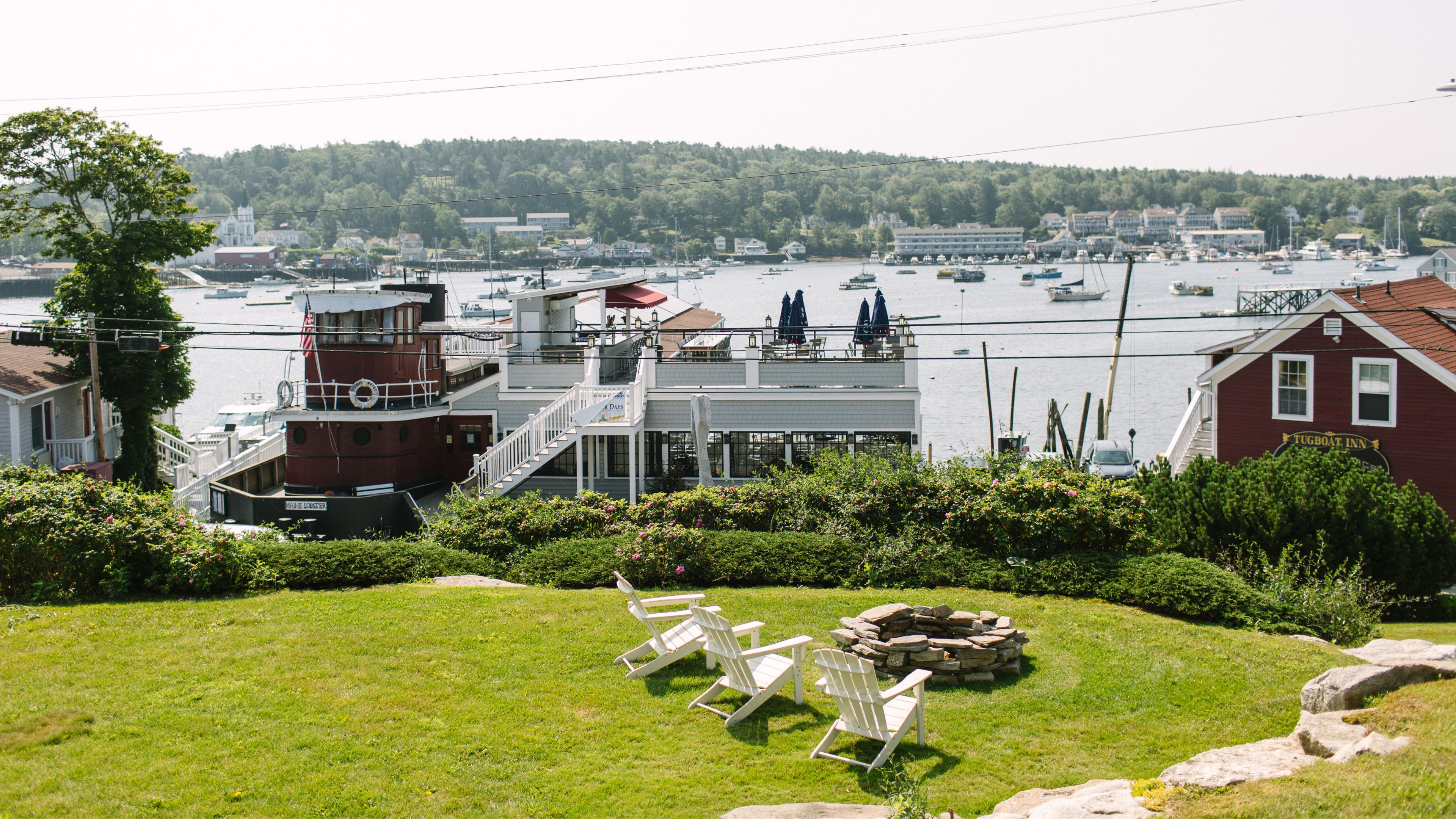 A waterfront property with a dock, a building with a balcony overlooking the water, and a grassy area with outdoor seating.