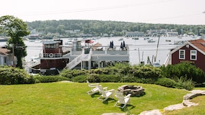 A waterfront property with a dock, a building with a balcony overlooking the water, and a grassy area with outdoor seating. - Penthouse B: Top-Floor King Suite, Shared Sky Deck, Greenleaf Inn, Boothbay (Boothbay Harbor)