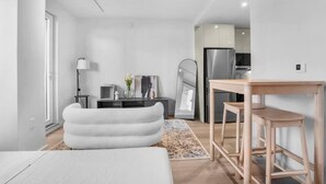 Um espaço de estar moderno e minimalista, com um sofá, uma mesa de jantar e uma área de cozinha ao fundo.