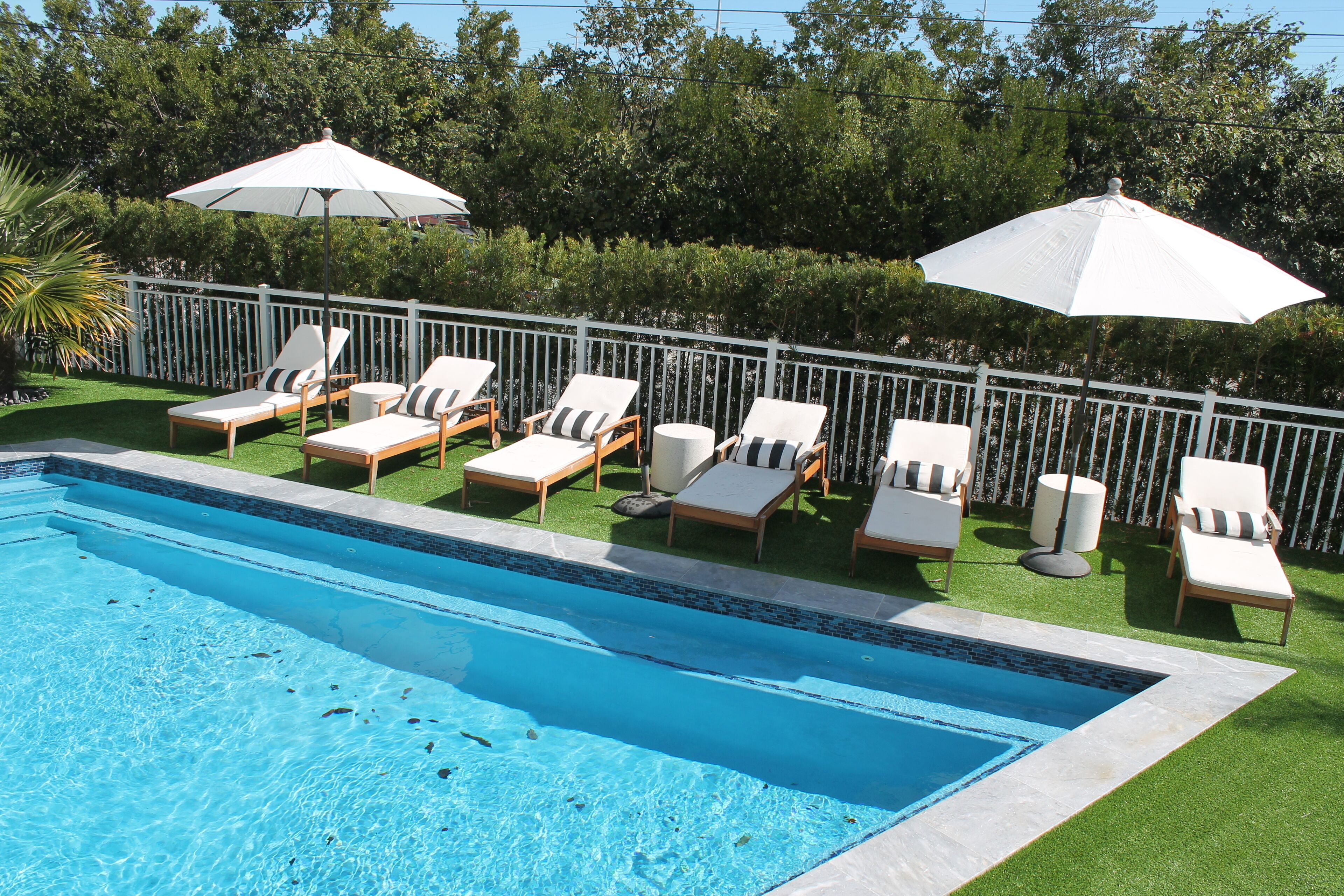 A swimming pool with lounge chairs and umbrellas.