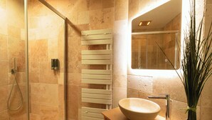 Un baño moderno con cabina de ducha de vidrio, toallero empotrado y tocador de madera con lavabo.