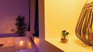 Una habitación con ventana, una planta pequeña en un frasco de vidrio y un objeto decorativo de metal sobre una estantería.