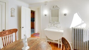 A room with a wooden dining table, a white sink with a decorative mirror, and a radiator.