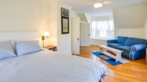A bedroom with a bed, a blue sofa, a nightstand, and a ceiling fan.