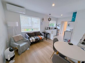Un espace de vie compact comprenant un canapé, une table à manger, un coin cuisine et une petite kitchenette.