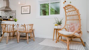 A modern kitchen with a herringbone backsplash, wooden chairs, a wicker chair with a cushion, and a small table with plants. - Mt. Rainier Getaway (Ashford)