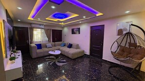 A modern living room with a sectional sofa, a hanging chair, and a coffee table. - A few steps away from the famous acropolis park, located in the heart of Apo! (Federal Capital Territory, Nigeria)