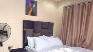A modern bedroom with a bed, bedside table, and a wall-mounted fan. - A few steps away from the famous acropolis park, located in the heart of Apo! (Federal Capital Territory, Nigeria)