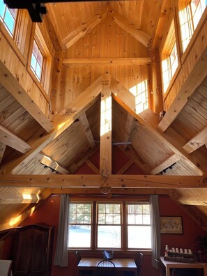 A wooden interior with a high ceiling, exposed beams, and large windows. - The Perfect Cozy Vermont Escape (Hinesburg)