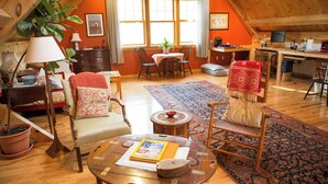 Um loft aconchegante com área de jantar, cozinha e sala de estar com piso de madeira e uma grande janela.