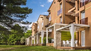 Un edifici d'apartaments modern amb balcons, zones d'estar a l'exterior i un jardí ben cuidat.