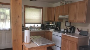 Una cucina compatta con mobili in legno, un fornello a gas, un forno a microonde e un lavello.