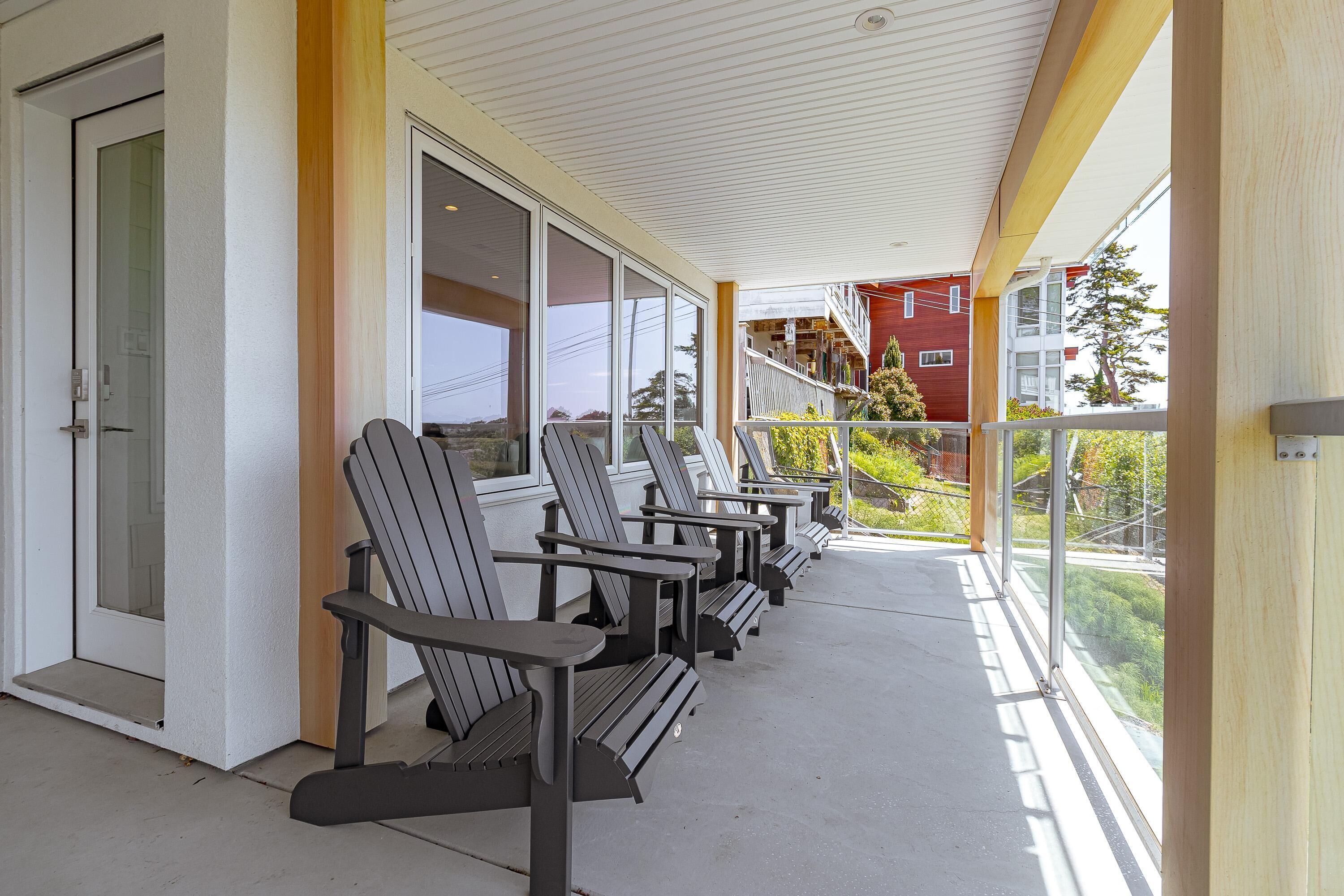 Un espace extérieur abrité, doté de chaises Adirondack et d’une entrée avec une porte vitrée.