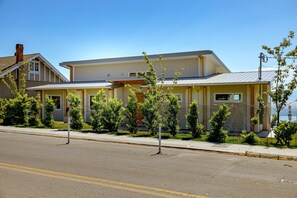 A two-story house with a front porch, a garage, and a small garden with young trees. - Premier Oceanfront Luxury in Oak Bay South (Oak Bay South)