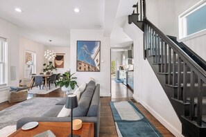 A modern living room with a sofa, coffee table, and dining area. - Luxury Boston Base · 2 Suites · 2 Baths · Red Line · Parking · Davis Square (Somerville)