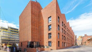 A modern brick building with a unique angular design, featuring multiple floors and a prominent entrance with steps. - Modern Liverpool Flat | Contractors & Work Trips % (Merseyside)
