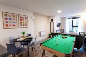 Ein Billardtisch mit grüner Spielbahn, eine Uhr an der Wand und gerahmte Bilder von Pokalen.