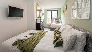 A bedroom with a bed, a TV, a dresser, and a window. - Modern Liverpool Flat | Contractors & Work Trips % (Merseyside)