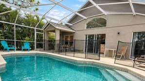 Ein Schwimmbecken mit Glasdach, umgeben von Liegestühlen und einer überdachten Terrassenanlage.