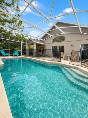A swimming pool with a glass ceiling, surrounded by lounge chairs and a covered patio area. - Spacious 5-bedroom house with Private Pool (Haines City)