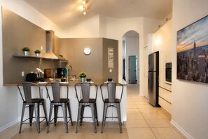 A modern kitchen with a central island, bar stools, and a refrigerator. - Spacious 5-bedroom house with Private Pool (Haines City)