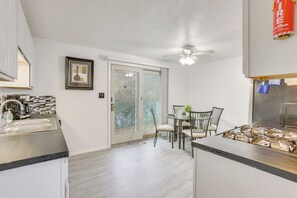 Eine moderne Küche mit Essbereich, Deckenventilator und einer Glastür, die auf eine Terrasse führt.