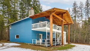 A two-story blue house with a wooden porch and a covered deck. - Silverwood Theme Park + Spirit Lake Retreat (Spirit Lake)