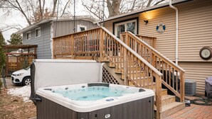 Ein Whirlpool in einem Garten mit einer Holztreppe, die zu einer Terrasse führt.