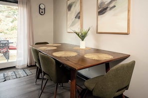 Ein Essbereich mit Holztisch, vier Stühlen, einem Blumentopf und abstrakter Kunst an der Wand.