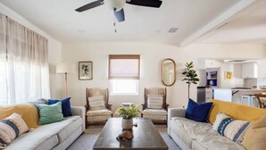 Un salon comprenant un canapé, des fauteuils, une table basse et un ventilateur de plafond.