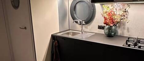 A modern kitchen with a built-in washing machine, a sink, and a vase with flowers.