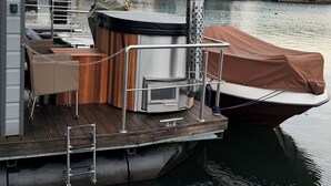 A floating deck with a hot tub, seating area, and a covered boat section. - Exclusive Houseboat 12 x 5 m with sauna and hot tub (Maasbommel)