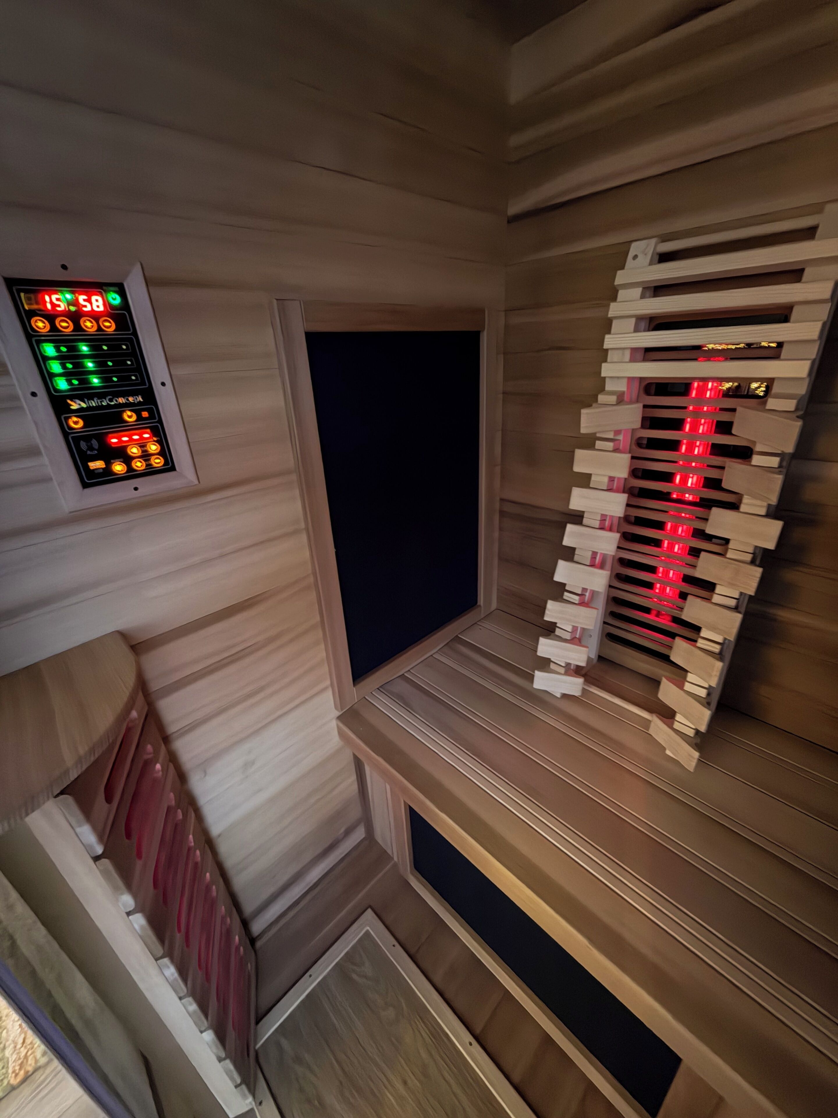 A room with a wooden panel wall, a control panel with green and red lights, and a wooden staircase with red lights.
