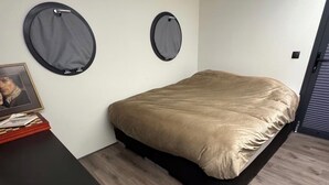 A compact bedroom with a bed, a small desk, and two circular wall decorations. - Exclusive Houseboat 12 x 5 m with sauna and hot tub (Maasbommel)