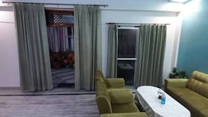 A living room with a sofa set, a coffee table, and a sliding glass door leading to a balcony.
