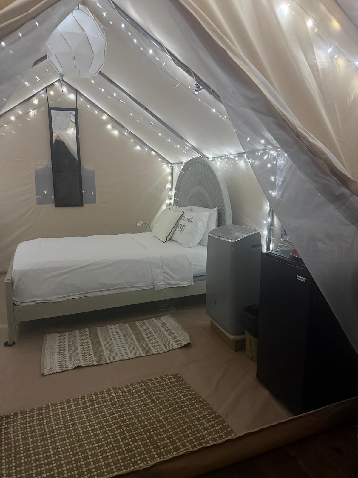 Une chambre confortable, aménagée comme une tente, avec un lit, une petite table et un radiateur.